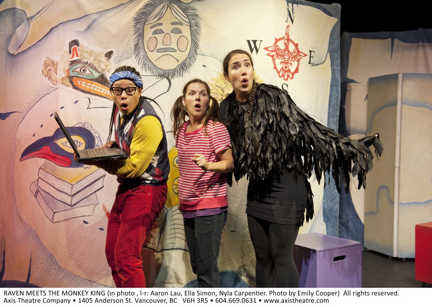 Three people, one with long braids and a bandana and holding a laptop, another dressed in casual clothing, and the third
dressed as a raven.