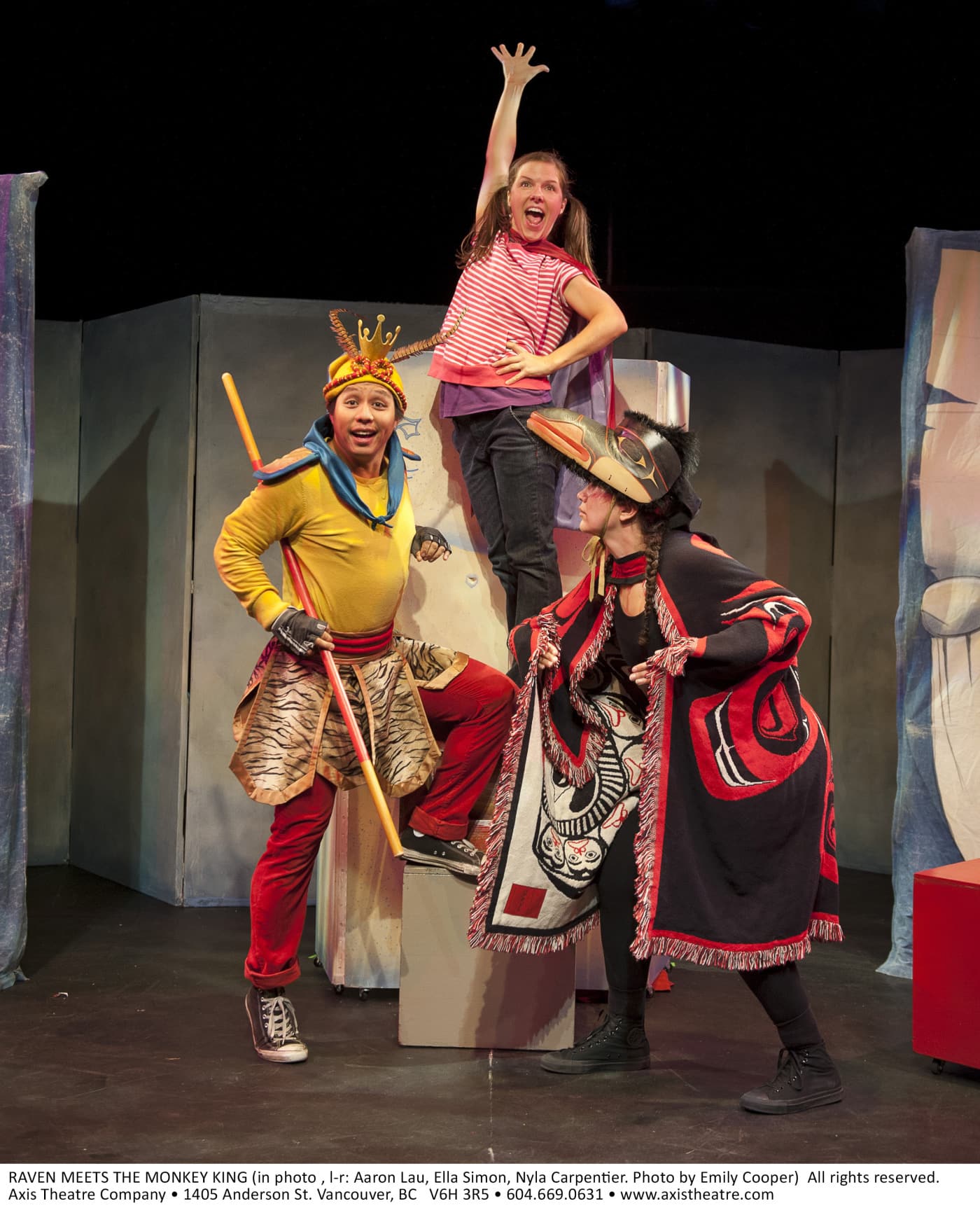 Three people are on stage and gesturing victory with their bodies.